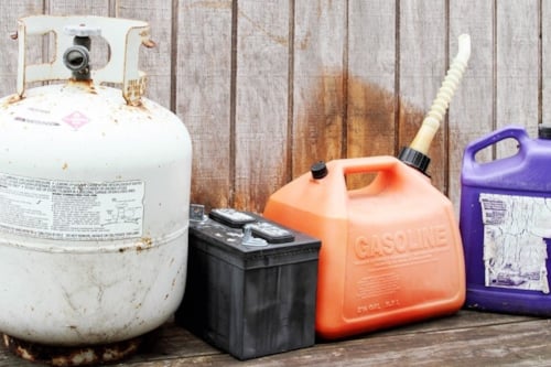 Behållare för kemikalier av olika slag: gasbehållare, bilbatteri, bensindunk och plastdunk för annan vätska.