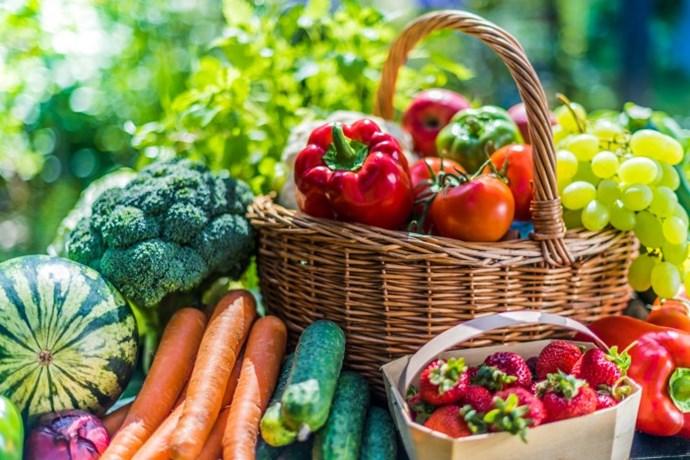 Vegetables and berries are displayed next to and in a basket.