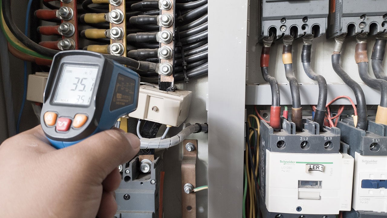 En elektriker använder en termopistol för att analysera underledningar och komponenter för att ta reda på överströmsbelastningar och avvikelser för en elanläggning.