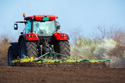 Traktor kör på åker